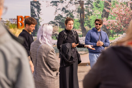 Een curator geeft uitleg aan een groep mensen over tentoongestelde fotografie